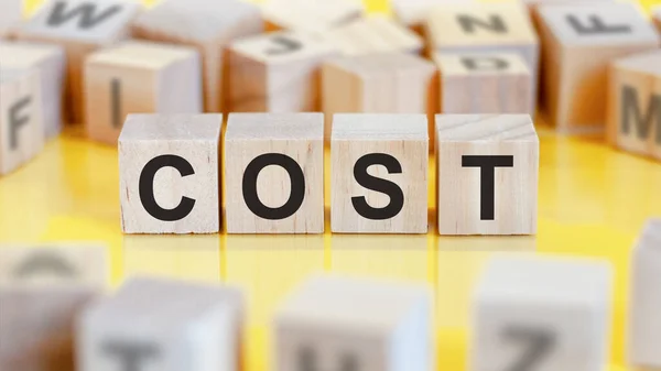 the word cost is written on a wooden cubes structure. blocks on a bright background. financial concept. selective focus.