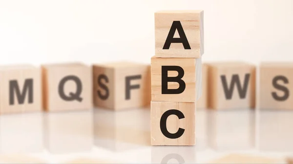 wooden cubes with letters ABC arranged in a vertical pyramid, white background, reflection from the surface of the table, business concept.