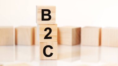 B2C harfli tahta küpleri dikey piramit şeklinde, beyaz arkaplan, masanın yüzeyinden yansıma, iş konsepti. b2c - tüketiciye iş yapmanın kısaltılmışı.