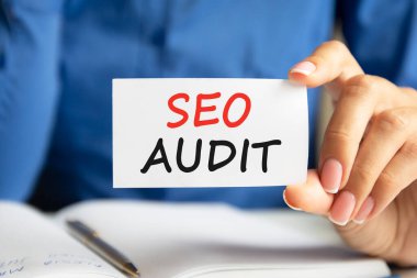 Seo denetimi bir kadının elindeki beyaz kartvizitle yapılır. Mavi arka plan. İş ve reklam kavramı