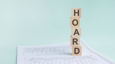 Kelime HOARD ile ahşap yapı taşları, açık yeşil arka plan. Geçmişinde numaralar olan bir belge, iş konsepti. Soldaki metin için boşluk. ön görünüm