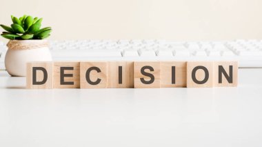 Tahta bloklardan yapılmış bir karar. Ön görüş kavramları, vazodaki yeşil bitki ve arkaplanda beyaz klavye