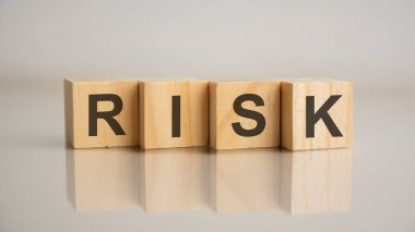 İçinde RISK harfleri olan dört tahta küp. İş pazarlama konsepti. Tablonun aynalı gri yüzeyindeki başlığın yansıması.