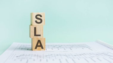 SLA harfli üç tahta küp. Beyaz masa ve diyagram üzerinde Hizmet Seviyesi Anlaşması, iş konsepti.