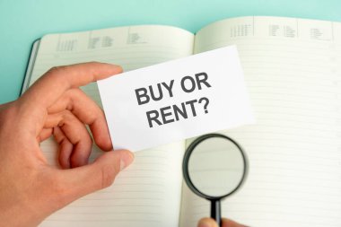 Bir adamın elinde açık bir defter ve siyah çerçeveli bir büyüteç üzerinde beyaz bir kart var. İş konsepti.