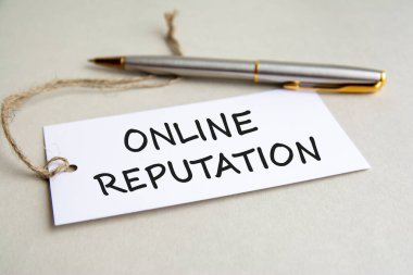 Gri arka planda metal kalemle çevrimiçi itibarlı beyaz kart