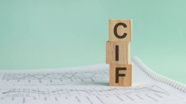 Beyaz mali tabloların arka planında üç taş küp, CIF harfli masalar - Acronim Maliyet Sigortası ve Nakliyesi. Güçlü iş konsepti. Gri arkaplan.