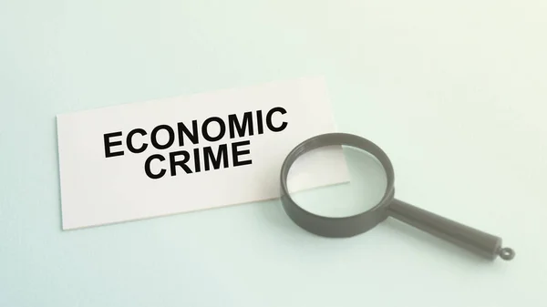 Economische criminaliteit woord op papier en vergrootglas — Stockfoto