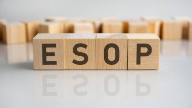 Esop - çalışanların hisse senedi sahipliği planı - Gri arkaplanda harfleri olan tahta bloklar. Tablonun aynalı yüzeyindeki başlığın yansıması. Seçici odak.