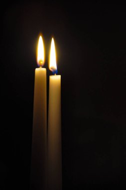 İki büyük yanan mum. Karanlık arka planda parlak bir ışık. Karanlık şablonu ayır. Doğum günü partisi. Sevgililer gününde romantik bir akşam..