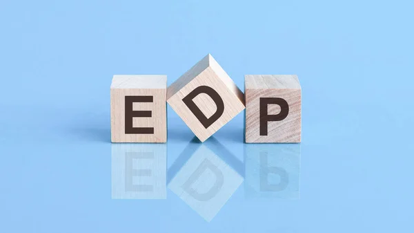 EDP word written on wood block. EDP word is made of wooden building blocks lying on the blue table, business concept. EDP short for Electronic Data Processing