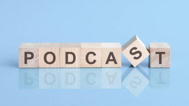 Tahta blokta podcast kelimesi yazılı. Podcast sözcüğü mavi masanın üzerinde duran ahşap yapı taşlarından yapılmıştır. iş kavramı