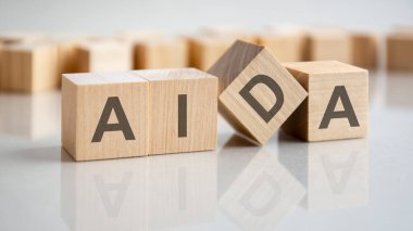 Gri bir masanın parlak yüzeyinde AIDA harfleri olan üç tahta küp. Küplerdeki yazıtlar masanın yüzeyinden yansıyor. iş kavramı.