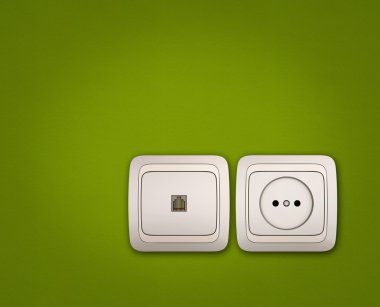 Bilgisayar ve yeşil duvardaki elektrik prizi