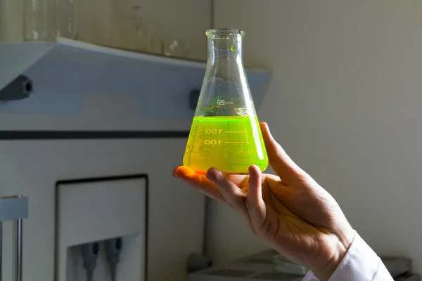 Líquido verde tóxico en la mano del químico — Foto de Stock