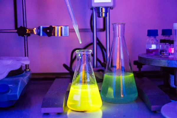 Frasco líquido verde tóxico en laboratorio químico bajo luz UV — Foto de Stock