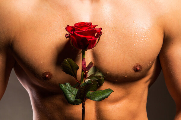 Человек с мускулистым туловищем держит розу
