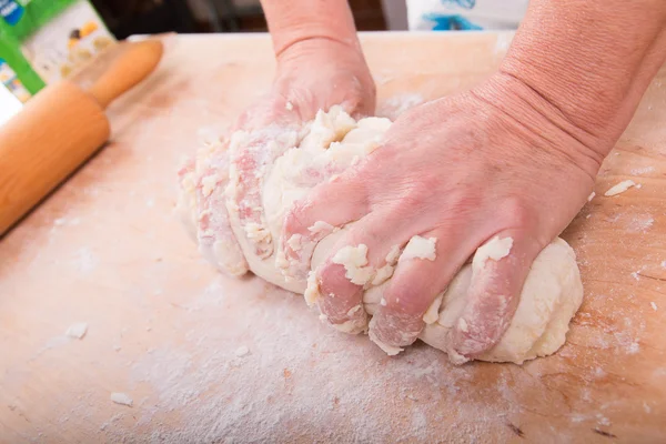 Hands kneading dough on board — Stock Photo, Image