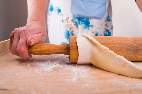 Desplegando la masa sobre una tabla en la cocina — Foto de Stock