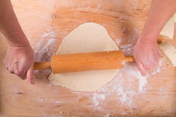 Rolling out the dough on a board in the kitchen — Stock Photo, Image