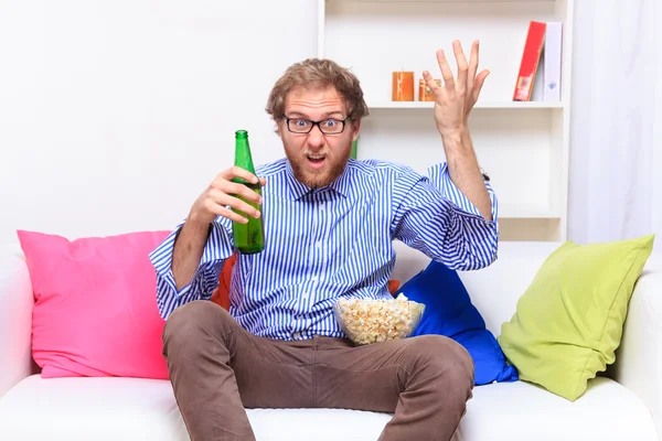 Dissatisfacted man on the couch when watching TV — Stock Photo, Image