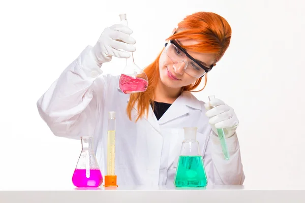 Mulher química olha para o vidro no laboratório — Fotografia de Stock