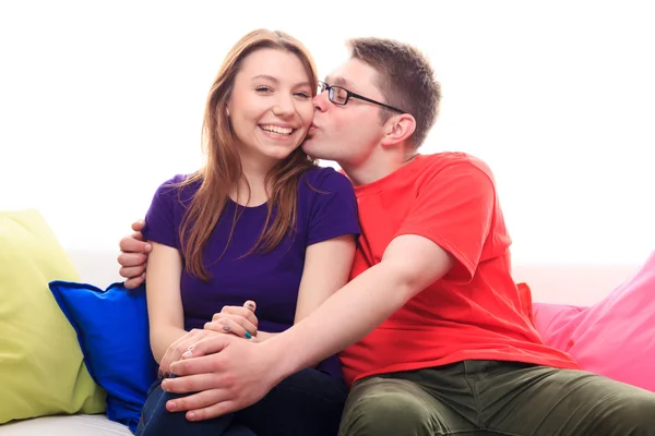 Menino beijando uma menina no sofá em casa — Fotografia de Stock