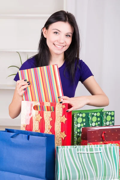 Glimlachend gelukkig meisje bereidt zakken cadeaus voor kerst — Stockfoto