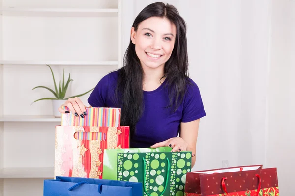 Smiling happy girl prepares bags gifts for Christmas — Stock Photo, Image