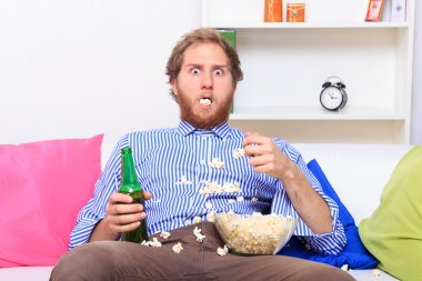 Şaşırmış adam yeme patlamış mısır Tv önünde