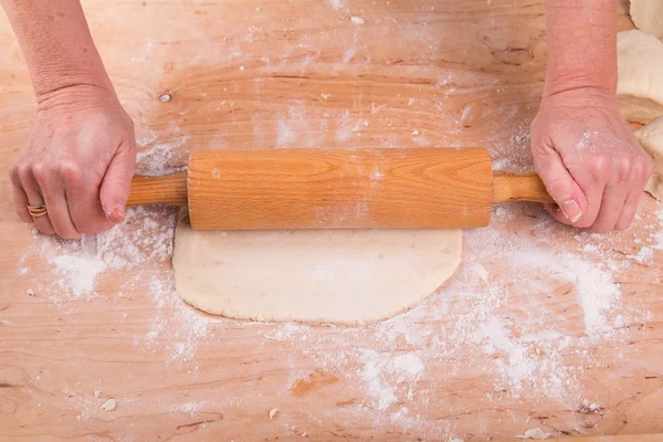 Rolling out the dough on a board in the kitchen — Stock Photo, Image