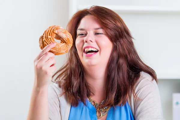 Plump and happy woman eating donuts at the table — Stock Photo, Image