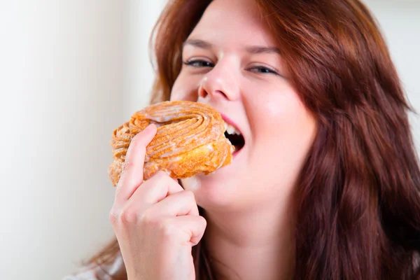 Mulher gorda e feliz comendo donuts na mesa — Fotografia de Stock