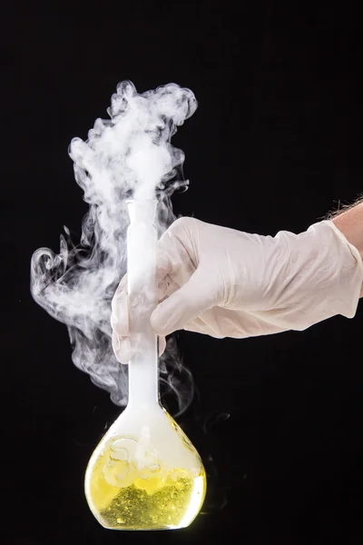 Réaction chimique dans le verre de fiole volumétrique maintenu dans les mains de — Photo