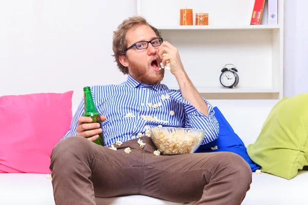 Man eating popcorn on  sofa — Stock Photo, Image