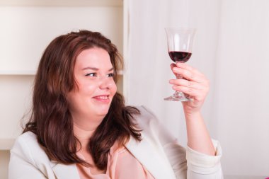 Dolgun ve genç kadın bir kadeh kırmızı şarap testleri