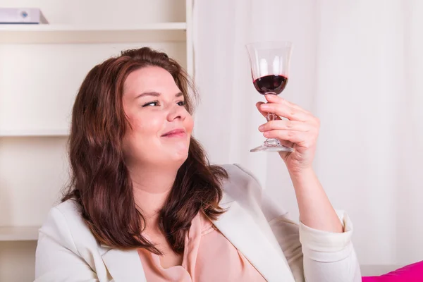 Plump and young woman tests a glass of red wine — Stock Photo, Image