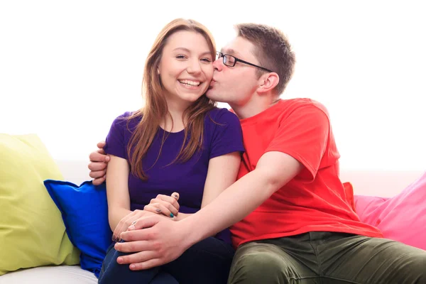 Menino beijando uma menina no sofá em casa — Fotografia de Stock