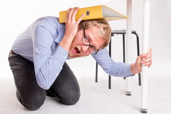 Aangevallen man verborgen onder het Bureau in het kantoor — Stockfoto