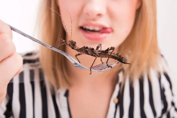 Woman eating insects with a fork in a restaurant — Stock Photo, Image