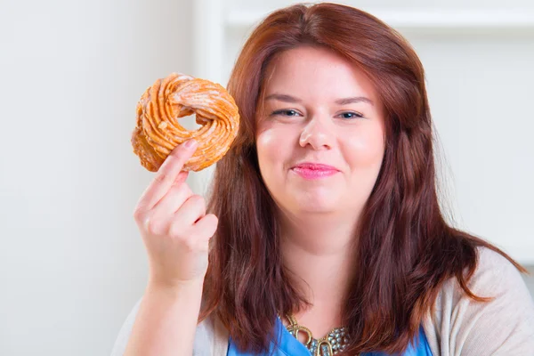 Mulher gorda e feliz comendo donuts na mesa — Fotografia de Stock