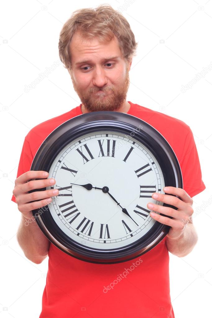Sad bearded man holding big clock on white 