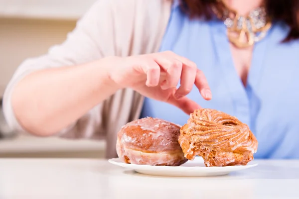Hand greift nach den süßen Donuts auf dem Tisch lizenzfreie Stockfotos