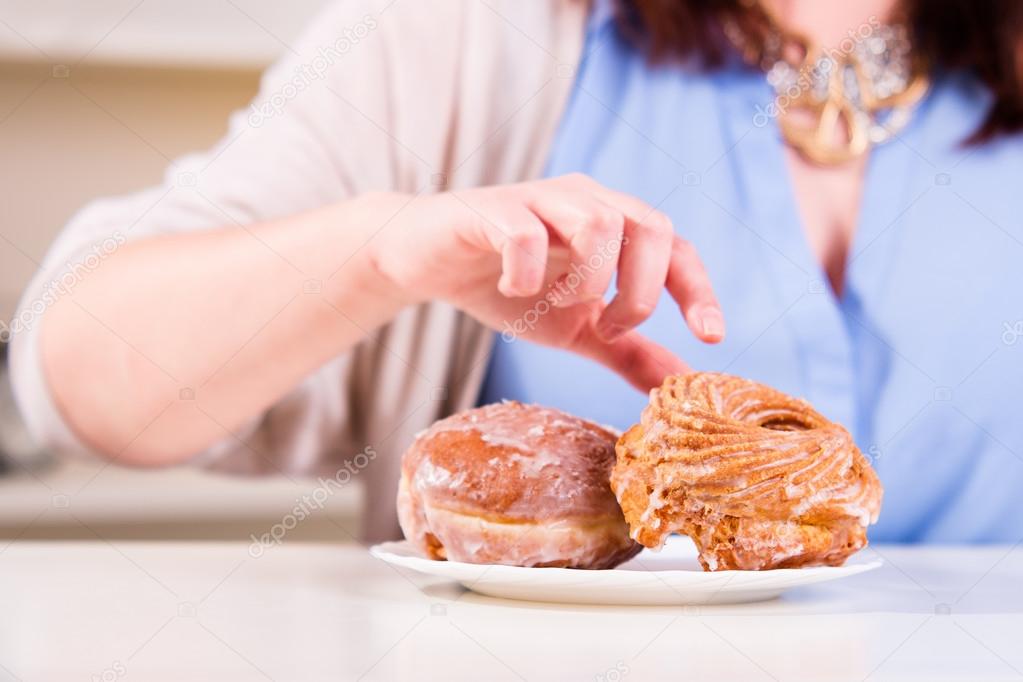 Hand reaches for the sweet donuts on the table