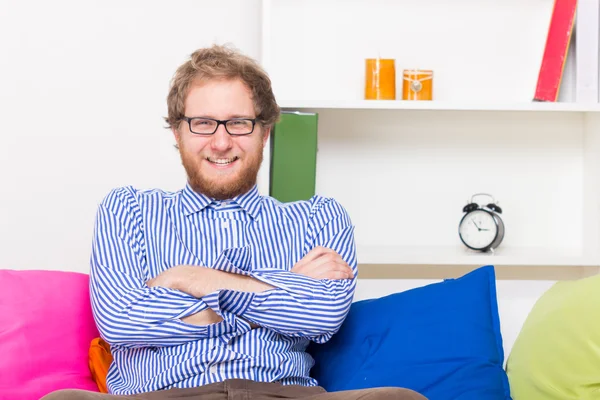 Бородатый улыбающийся мужчина сидит на диване — стоковое фото