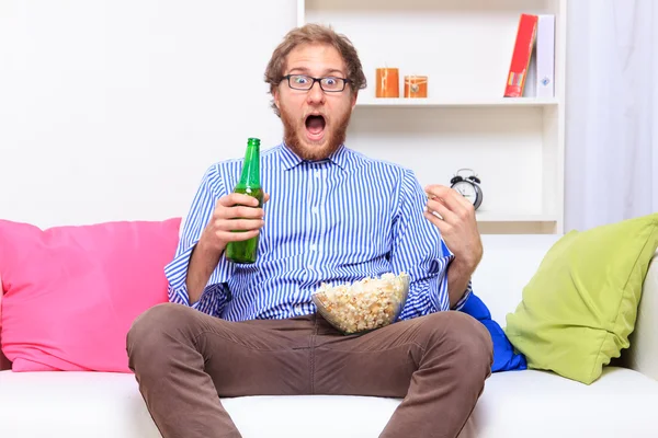 Surprised guy watching TV with beer — Stock Photo, Image