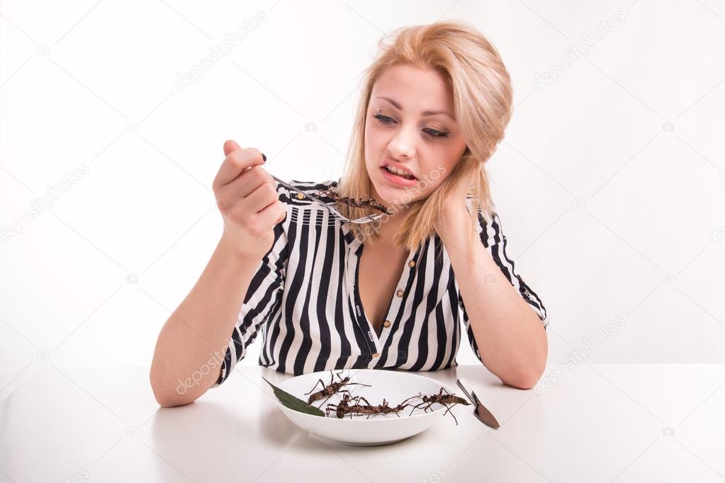 Disgusted woman eating big insects