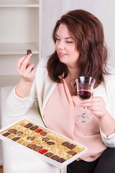 Plump woman with sweets and wine — Stock Photo, Image