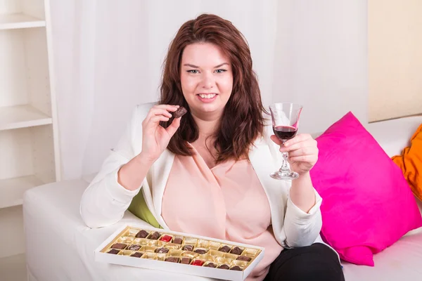 Plump woman with sweets and wine — Stock Photo, Image