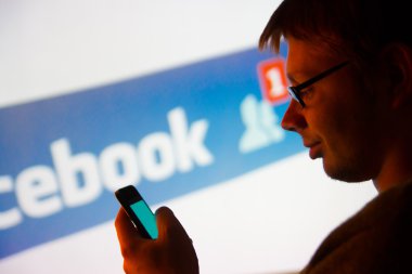 Facebook uygulaması smartphone kullanan adam